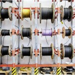 Mehrere verschiedene Kabelrollen mit Kabeln neben- und übereinander an einer Stahlkonstruktion angebracht