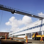 Bauarbeiter stapeln lange Eisenstangen mithilfe eines Krans