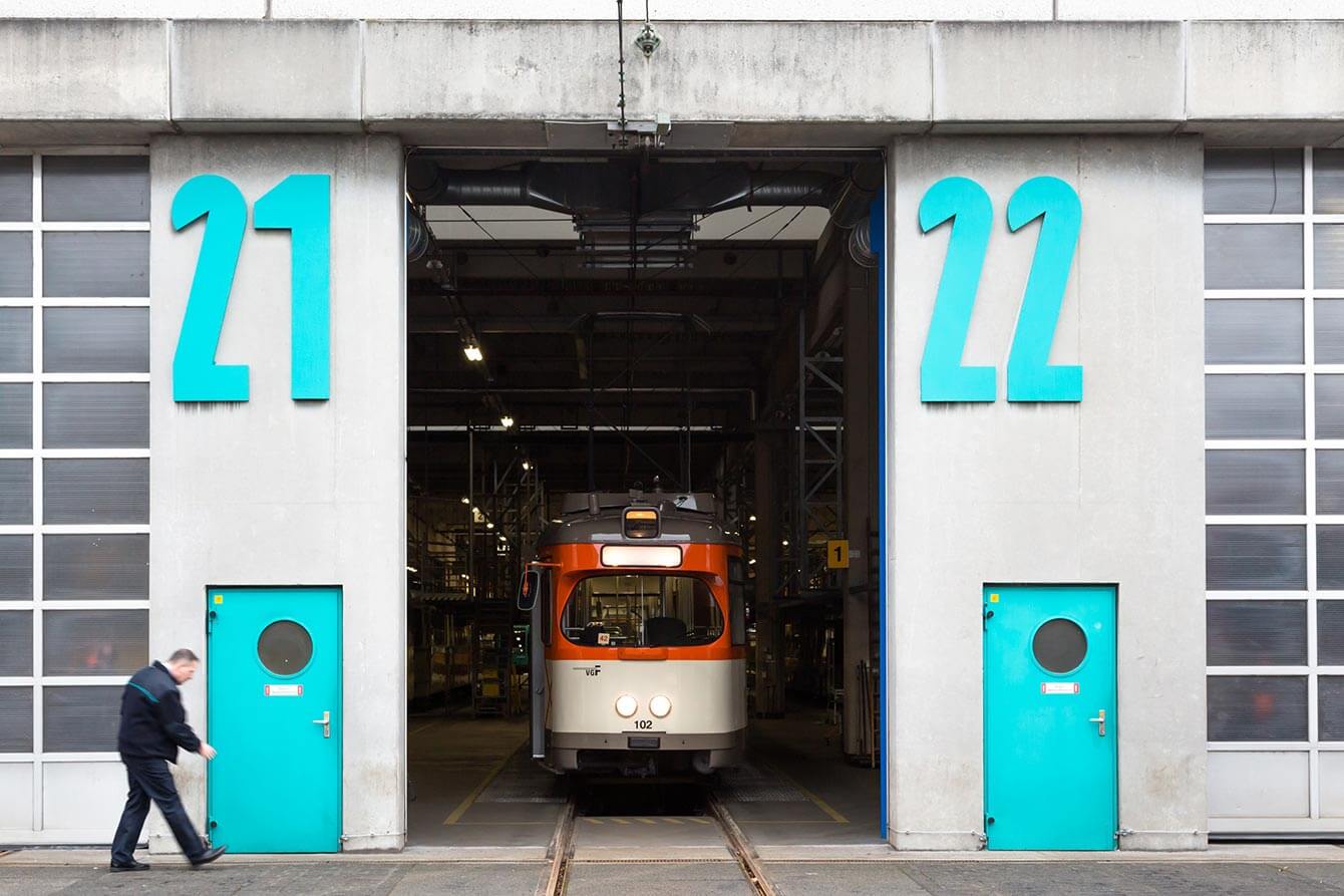 Halle mit großen VGF-grünen Zahlen 21 und 22 auf der Fassade, darunter in der selben Farbe jeweils eine Tür und dazwischen eine Oldtimer-Bahn