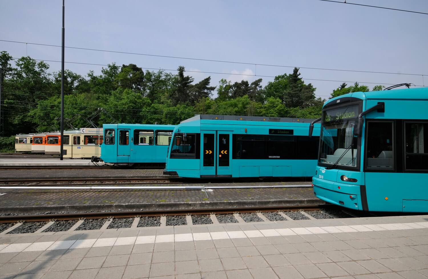 Sieben Straßenbahnen versetzt hintereinander auf den Gleisen stehend von alt (hinten) bis neu (vorne)