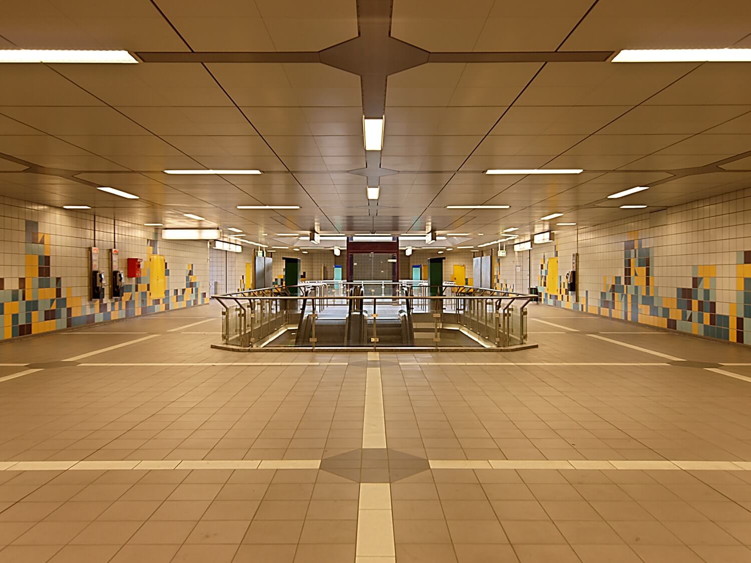 Komplett gefliester Gang der B-Ebene des Ostbahnhofs. Mitte die Treppe und Fahrtreppe, dahinter der Aufzug.