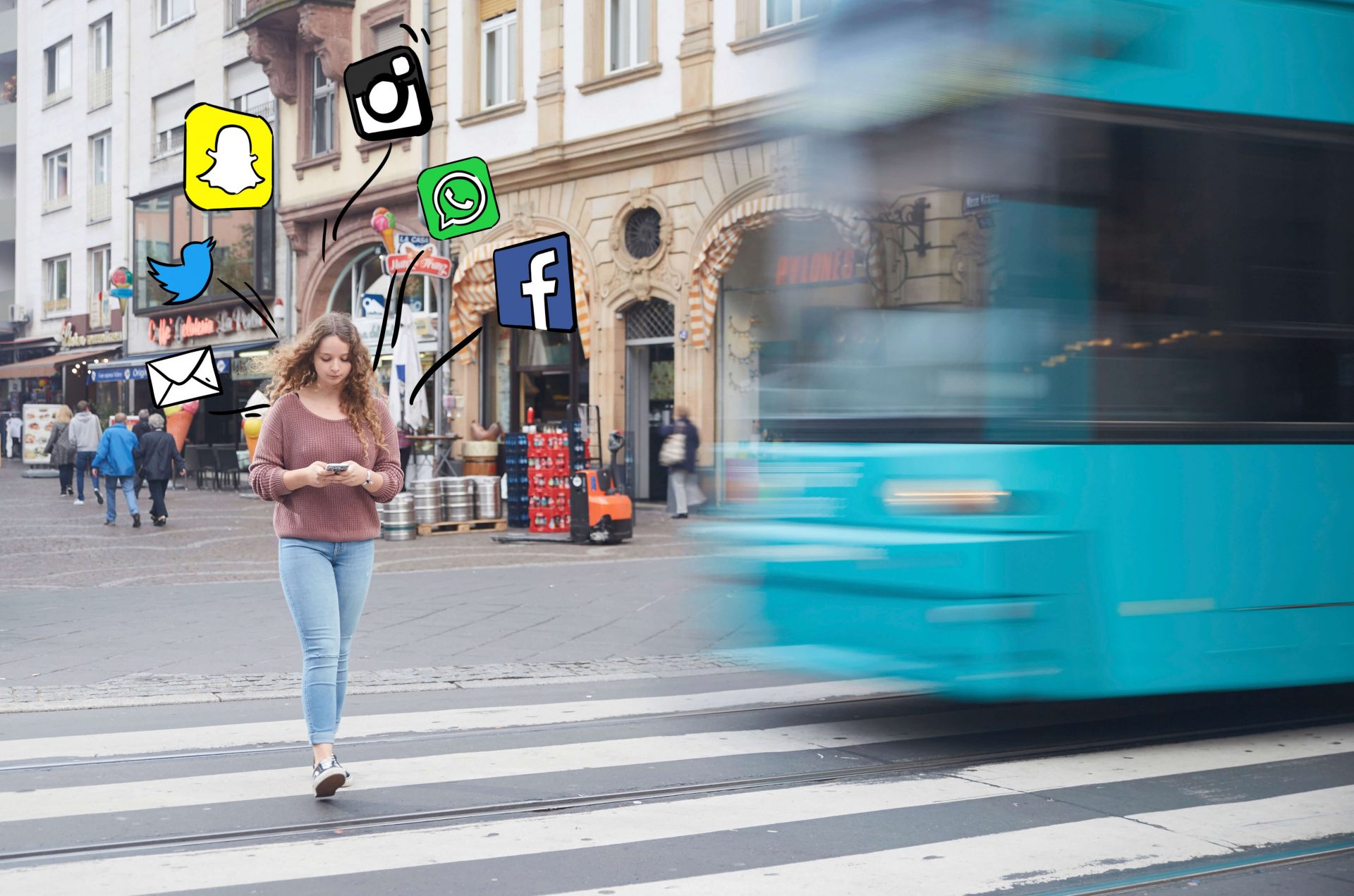 Junge Frau schaut beim Überqueren der Schienen über einen Zebrastreifen auf ihr Handy, um sie herum sind Social Media Icons gemalt, während die Bahn näher kommt.