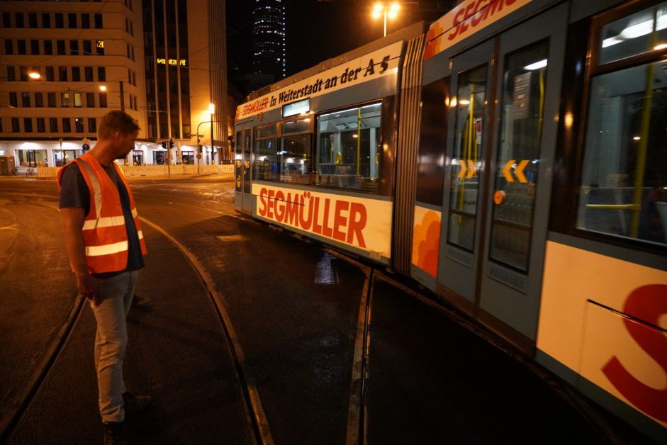Bauarbeiter betrachtet Straßenbahn bei Nacht